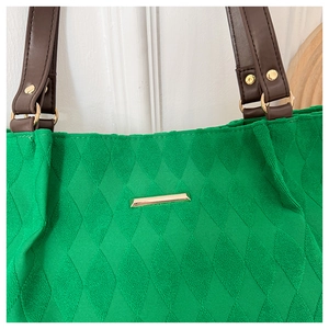 Dettaglio borsa tote trapuntata verde con tracolla in pelle e finiture metalliche d'oro