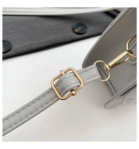 Close-up of adjustable faux leather shoulder strap with gold metal buckle and stitching