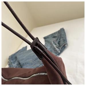 Macro shot of brown tote bag showing fabric stitching, suede detail, and silver hardware