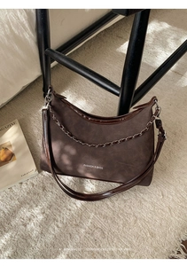 Gros plan du sac cabas en daim marron foncé avec chaîne en métal et texte imprimé