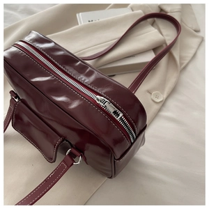 Detail of burgundy PU leather bowling bag showing contrast stitching and silver zipper