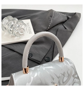 Detail of silver metallic handbag featuring jacquard pattern and gold-tone hardware buckles