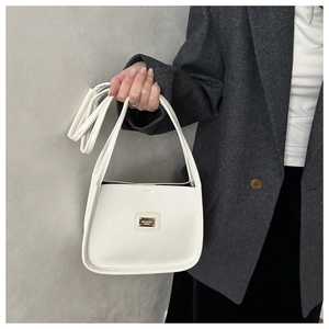 Détail du sac à bandoulière blanc minimaliste avec plaque en métal doré sur veste grise