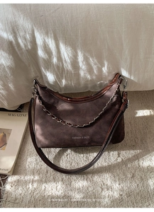 Détail du sac bandoulière vintage en croissant avec texture suède et chaîne métallique