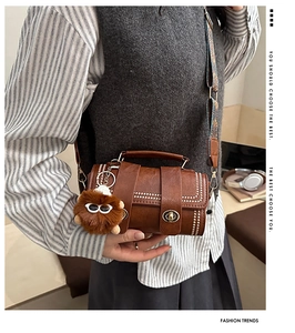 Close-up of vintage brown barrel bag featuring metal rivets and patterned strap