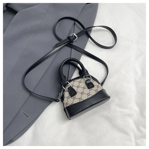 Detailed view of plaid shell bag with black leather handle and adjustable strap