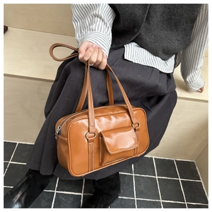 Close-up of caramel leather shoulder bag with white contrast stitching and pocket detail