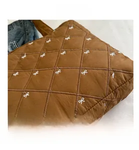 Dettaglio della borsa tote in nylon trapuntato marrone con fiocchi bianchi ricamati