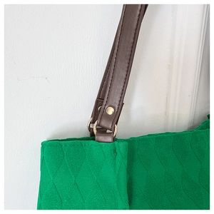 Dettaglio della borsa tote trapuntata verde con manici in pelle e anelli dorati