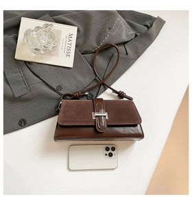 Close-up of retro brown shoulder bag with suede flap and silver buckle detail