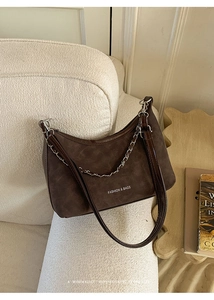 Gros plan d'un sac seau en daim marron avec chaîne et inscription Fashion & Bags