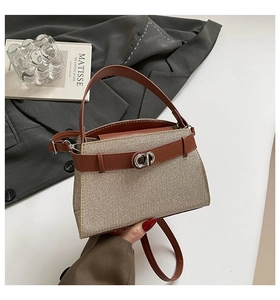 Close-up of woven texture and leather trim with silver metal turn-lock on handbag