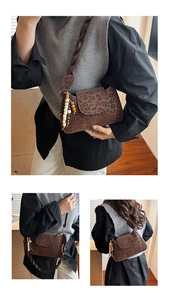 Detailed view of brown leopard print baguette bag with woven strap and bead charm