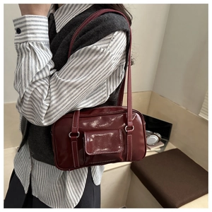 Detail of burgundy patent leather Boston bag with white stitching and front pocket flap