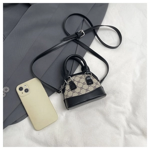 Close-up of mini shell bag featuring vintage monogram canvas and black leather handles