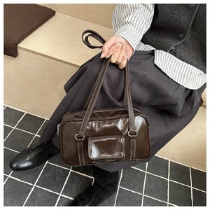 Detail of dark brown high-shine tote with white contrast stitching and silver hardware