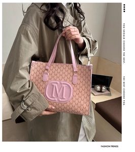 Detail of pink tote bag with brown M pattern and round embossed logo for women