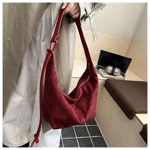 Detail of burgundy suede hobo bag with adjustable strap in a lifestyle office setting