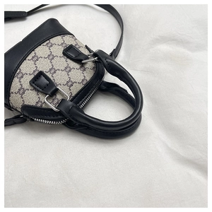 Close-up of mini shell bag with black Triomphe patterns and silver zipper hardware