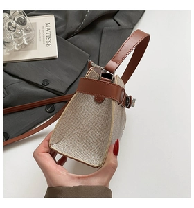 Close-up of champagne gold sequin handbag with brown leather strap and silver metal buckle