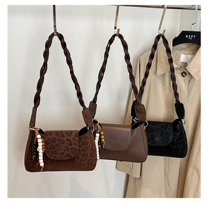 Detail of elegant shoulder bags with braided straps and decorative bead charms