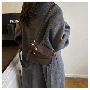 Detailed side view of brown lychee leather handbag with golden studs and metal lock