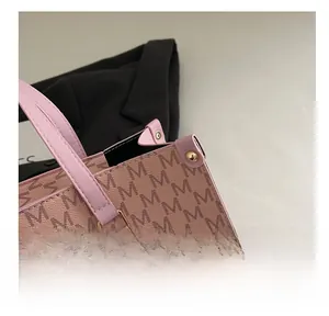 Close-up of pink tote bag with brown monogram pattern and golden metal rivet detail