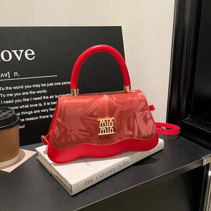 Elegant red leather handbag with gold logo and graffiti texture on white books