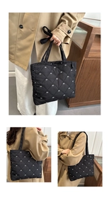 Dettaglio della borsa tote trapuntata nera con ricamo a fiocco bianco e motivo a rombi