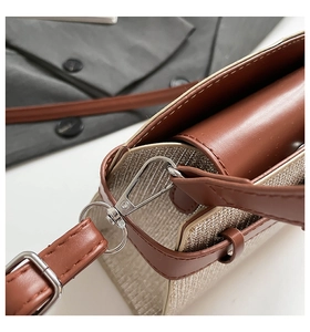 Close-up of silver metal hardware and fine stitching on a brown leather shoulder bag