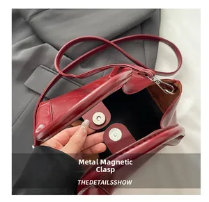 Detailed macro view of the secure dual magnetic snap closure on a red leather tote bag