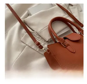 Dettaglio della borsa in pelle marrone con tracolla regolabile e fibbia dorata