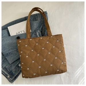 Vista dettagliata della borsa tote marrone trapuntata con motivi a fiocco bianchi