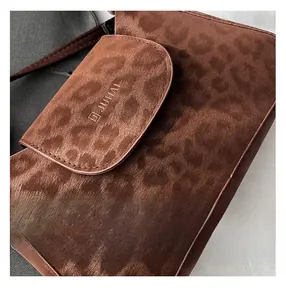 Macro shot of brown leopard print texture and brand logo on a retro shoulder bag