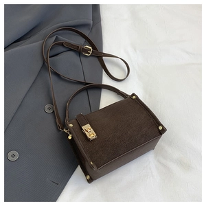 Detail view of a vintage dark brown box bag with gold metal twist lock and suede texture
