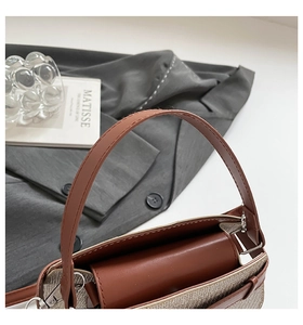 Close-up of woven canvas texture with brown leather handle and silver metal hardware detail