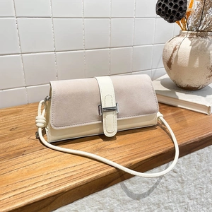 Retro baguette shoulder bag with cream leather and grey suede patchwork flap on a wooden shelf
