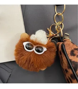Macro shot of a brown plush ball charm with sunglasses and a white knitted mini hat