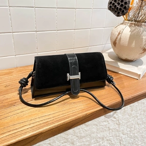 Retro black baguette shoulder bag with suede and leather patchwork on wooden table