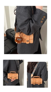 Detail of brown vintage crossbody bag with contrast stitching and patterned strap