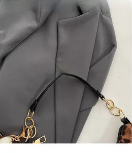 Detail of leopard print crescent bag featuring gold metal chain and black handle