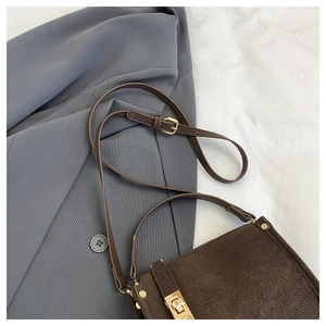 Close-up of vintage dark brown faux leather bag with adjustable strap and gold buckle