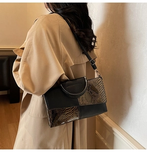 Detail der quadratischen Tasche aus schwarzem Leder mit Schlangenmuster und Metallgriff