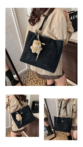 Detail of black leather tote bag with a cute brown plush bear charm and gold metal logo