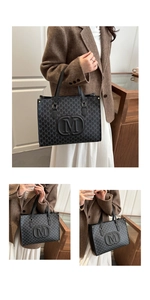 Detail of black tote bag featuring M-letter pattern and embossed logo held by model