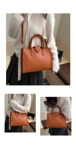Detail of orange textured leather tote bag showing handle and detachable shoulder strap