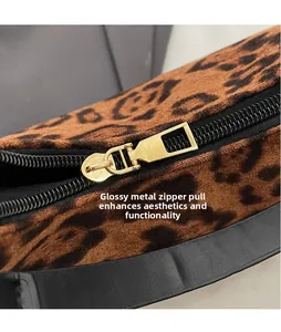 Close-up of golden metal zipper puller on leopard print shoulder bag with fine texture