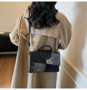 Detail einer Handtasche mit Schlangenmuster-Patchwork zu einem beigen Trenchcoat