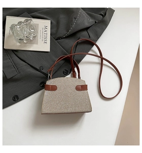 Detail of glitter fabric handbag with brown leather trim and slim shoulder strap