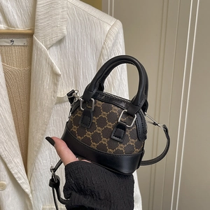 Mini winter shell crossbody bag with brown monogram pattern held in hand for scale